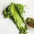 Green powder with a spoon on a white background